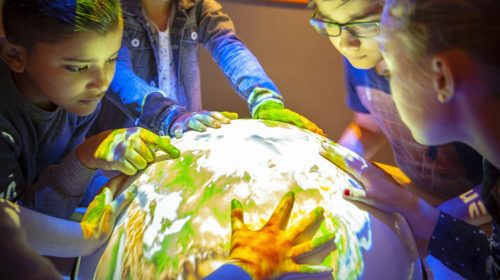 Kinderen om een grote verlichte globe