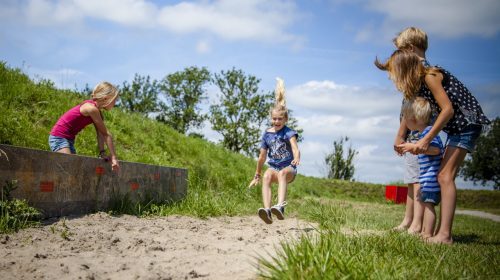 Kinderen springen over zandbakken in de speurtuin