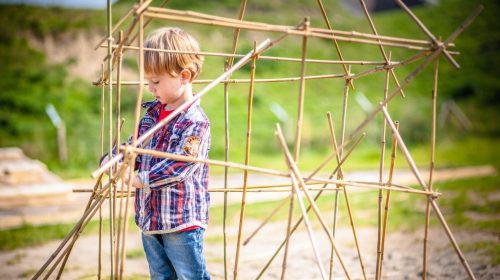 Jongetje bouwt met bamboestokken in de speurtuin