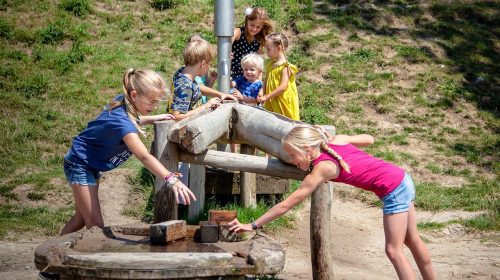 Kinderen spelen met de waterpomp in de speurtuin