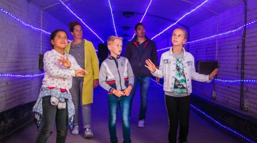Kinderen lopen door de paars verlichte forttunnel